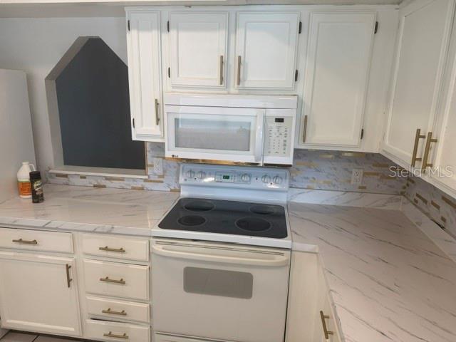 A kitchen with white cabinets, a white electric stove, and marble-patterned countertops — 2602 GRAMERCY DRIVE, DELTONA, FL
