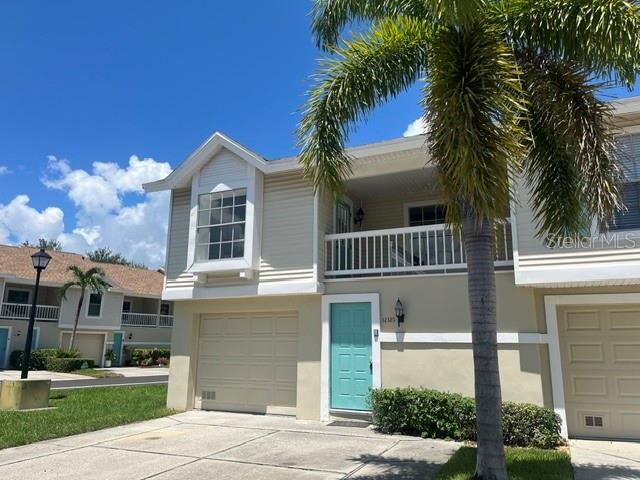 A two-story townhouse with beige siding, a teal front door, and a palm tree — 12325 SUN VISTA COURT W, TREASURE ISLAND, FL