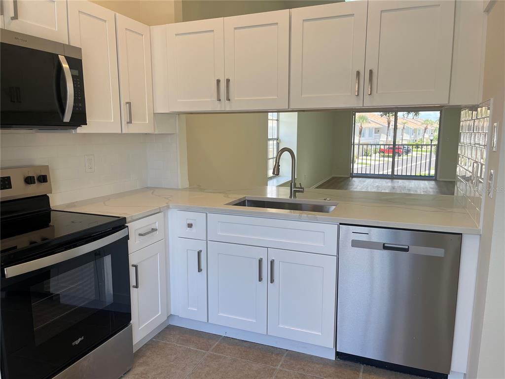 A kitchen with white cabinets, stainless steel appliances, and light-colored countertops — 12325 SUN VISTA COURT W, TREASURE ISLAND, FL