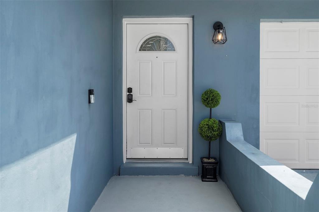 A white front door with a semi-circular window sits on a blue porch — 6917 DUNNETT AVENUE N, ST PETERSBURG, FL
