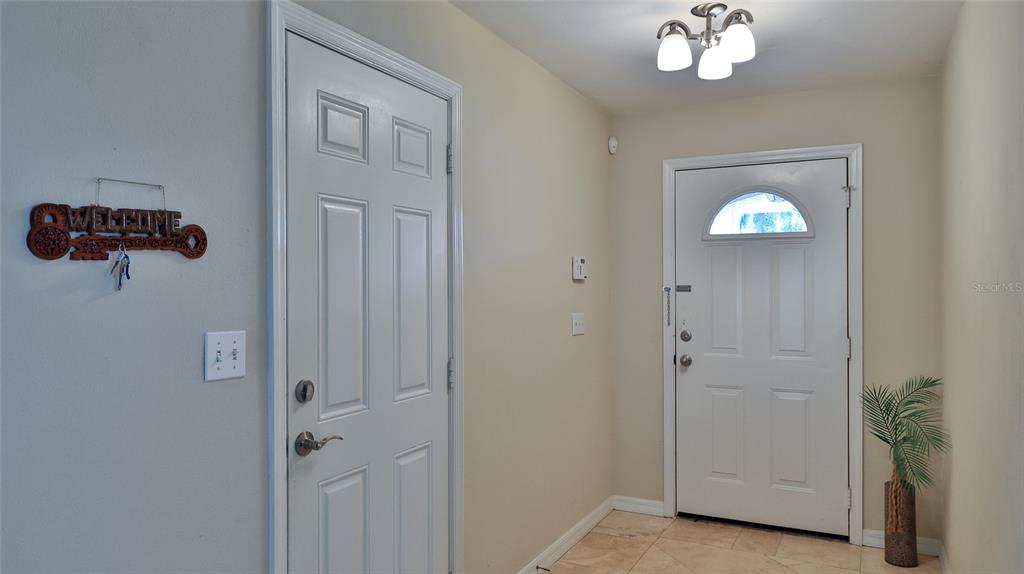 An entryway features two white doors, a light fixture, and a small potted plant — 6171 SABAL POINT CIRCLE, PORT ORANGE, FL