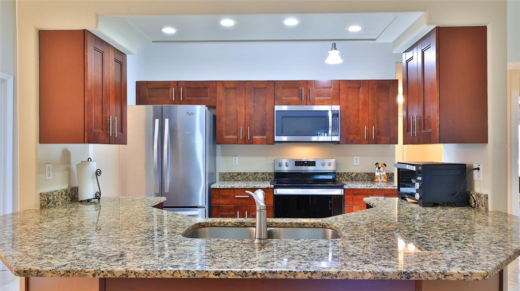 A kitchen features wood cabinets, granite countertops, stainless steel appliances, and a breakfast bar — 6171 SABAL POINT CIRCLE, PORT ORANGE, FL