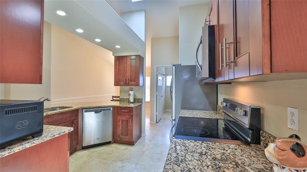 A kitchen features wood cabinets, granite countertops, stainless steel appliances, and tile flooring — 6171 SABAL POINT CIRCLE, PORT ORANGE, FL