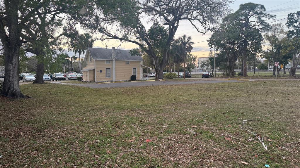 A light-colored two-story house sits behind a large, grassy lot with mature trees — 1505 6TH AVENUE W, BRADENTON, FL