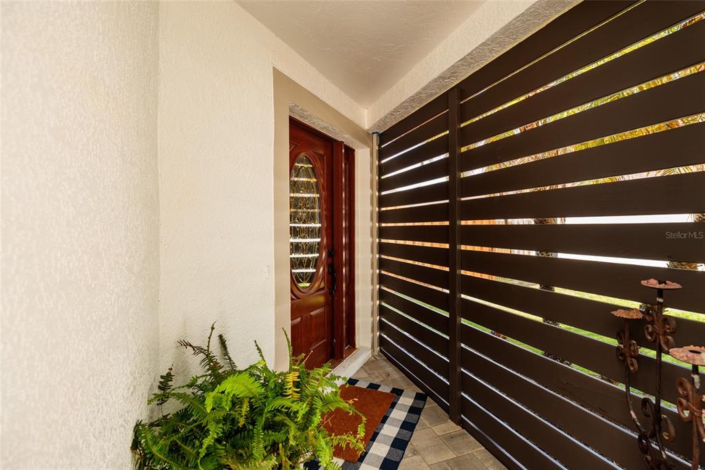 A front entryway features a wooden door with an oval glass insert and slatted privacy screen — 4909 70TH STREET E, PALMETTO, FL
