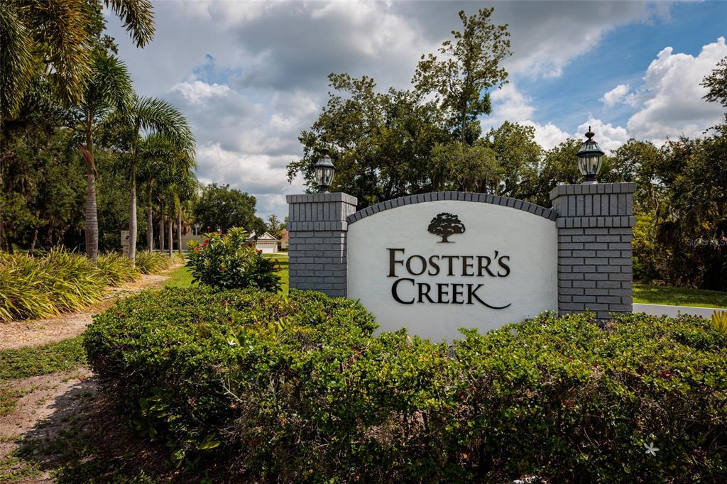 A brick-columned monument sign for Foster's Creek stands amidst lush landscaping and palm trees — 4909 70TH STREET E, PALMETTO, FL
