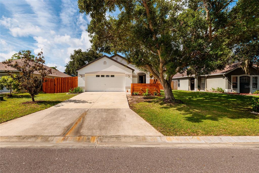 A single-story house with a white exterior, a two-car garage, and a large front tree — 4909 70TH STREET E, PALMETTO, FL