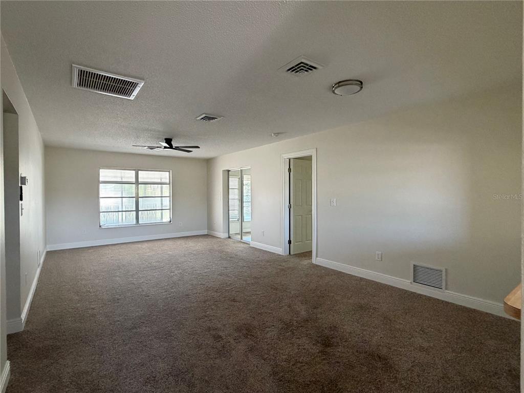 An empty room with beige carpet, a ceiling fan, a window, and a doorway — 635 HARVEY STREET, ENGLEWOOD, FL
