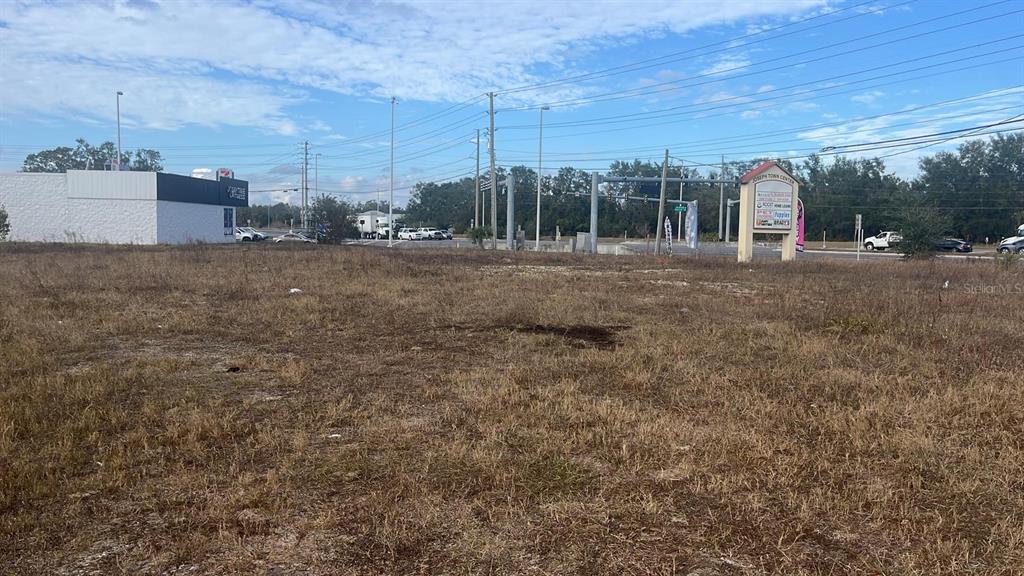 A vacant, grassy lot sits in front of a commercial shopping center and road intersection — 2401 GRIFFIN ROAD UNIT E, BARTOW, FL