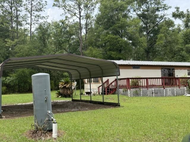 A metal carport stands in a grassy yard in front of a mobile home with decking — 4890 NW 55TH AVENUE, BELL, FL
