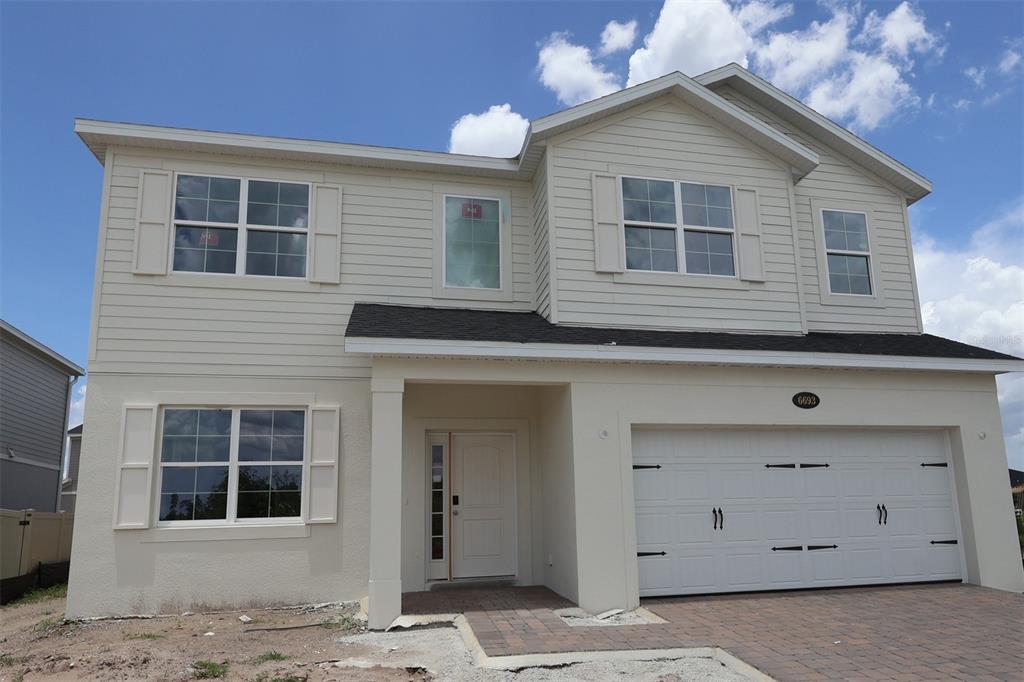 A modern kitchen features white cabinetry, a central island, and stainless steel appliances — 6693 YELLOW WARBLER BEND, ST CLOUD, FL