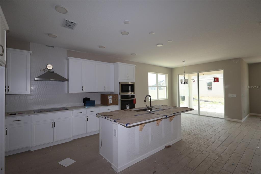 An empty room with beige walls, white baseboards, two electrical outlets, and unfinished concrete flooring — 6693 YELLOW WARBLER BEND, ST CLOUD, FL