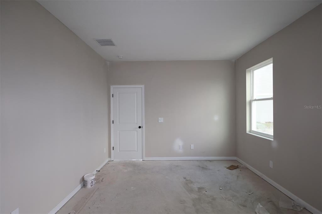 An empty bedroom features neutral walls, a tray ceiling, three windows, and an open doorway — 6693 YELLOW WARBLER BEND, ST CLOUD, FL