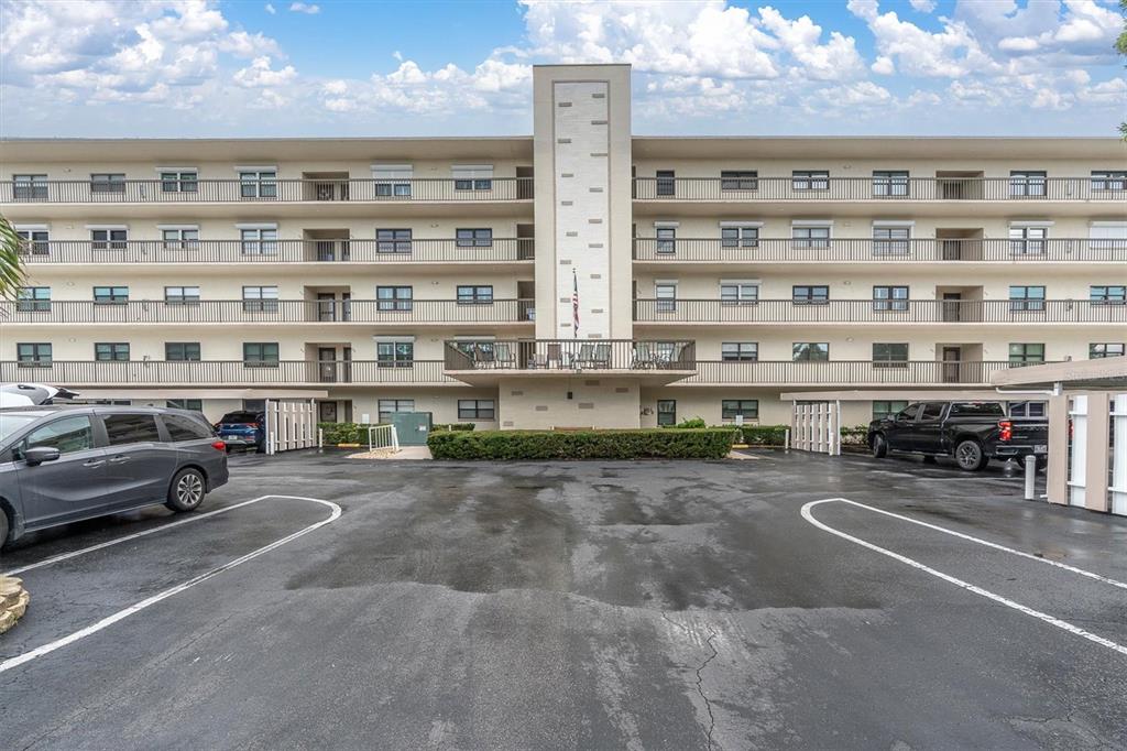 A multi-story apartment building with balconies and a parking lot in the foreground — 8198 TERRACE GARDEN DRIVE UNIT 511, ST PETERSBURG, FL