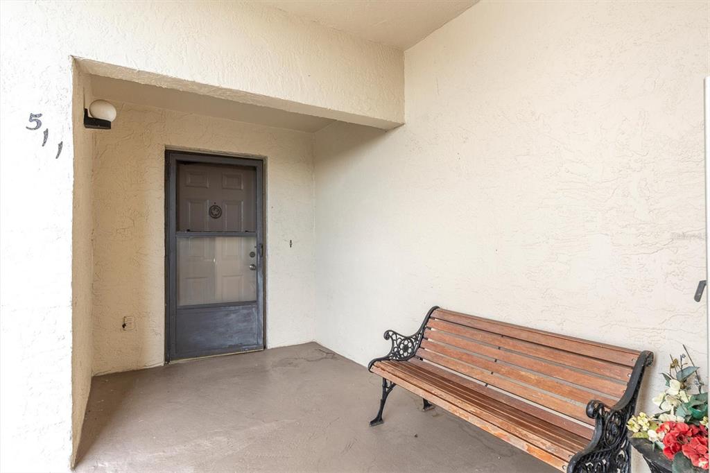 A covered entryway features a wooden bench, a storm door, and the number 511 — 8198 TERRACE GARDEN DRIVE UNIT 511, ST PETERSBURG, FL