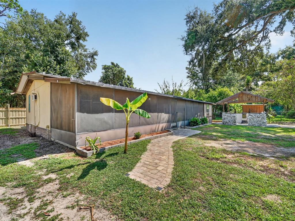 A screened-in porch exterior with a stone-paved walkway and a small outdoor pavilion nearby — 25101 NE 131ST PLACE, FORT MC COY, FL