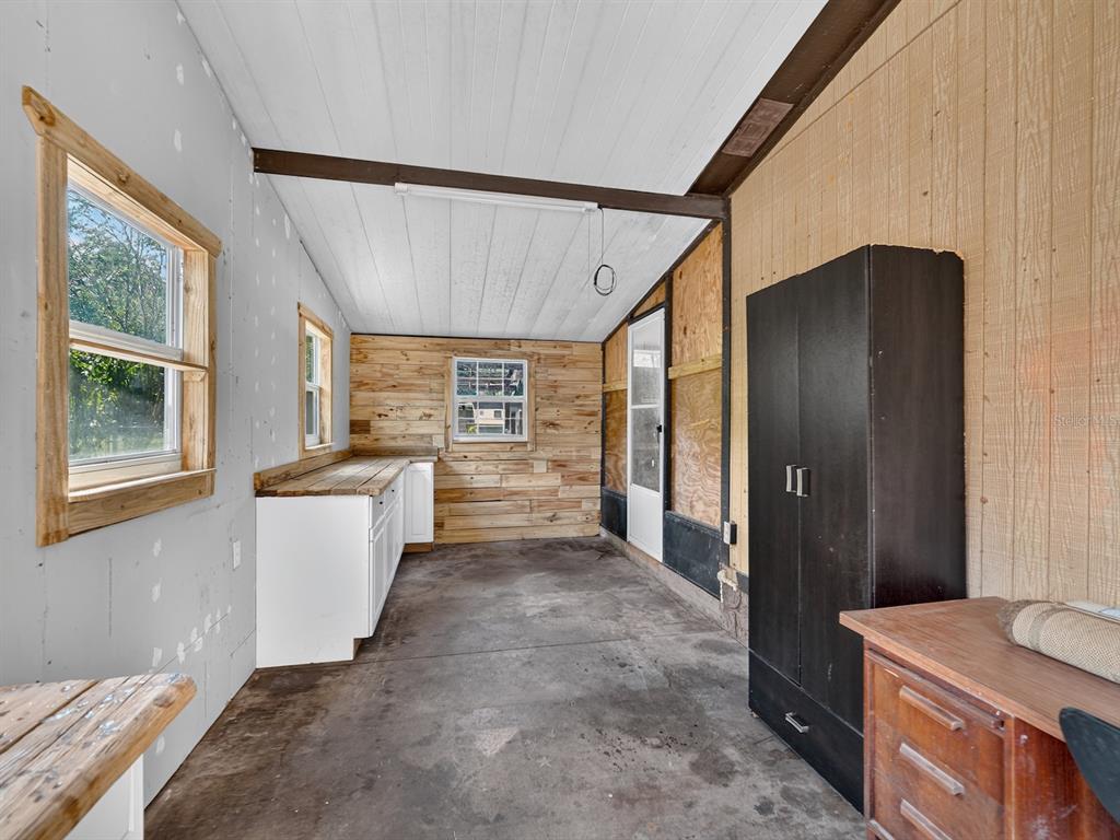 A utility room with a concrete floor, wood-paneled walls, white cabinets, and a black wardrobe — 25101 NE 131ST PLACE, FORT MC COY, FL
