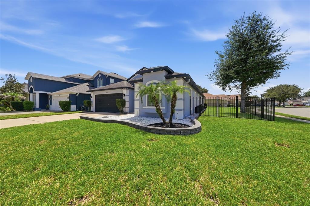 A single-story house with a gray exterior, a two-car garage, and a fenced side yard — 4037 WARWICK HILLS DRIVE, WESLEY CHAPEL, FL