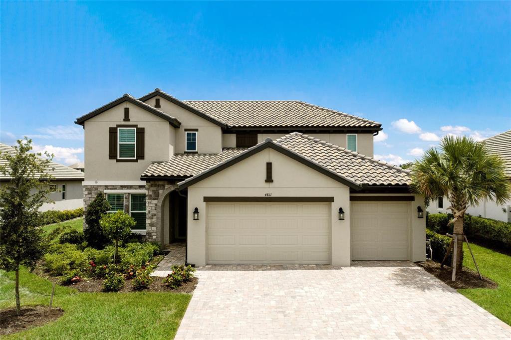 A two-story suburban house features a beige stucco exterior, stone accents, and a three-car garage — 4811 HONEY DEW LANE, BRADENTON, FL