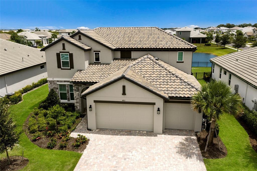 An aerial view of a two-story suburban house with a tiled roof and paver driveway — 4811 HONEY DEW LANE, BRADENTON, FL