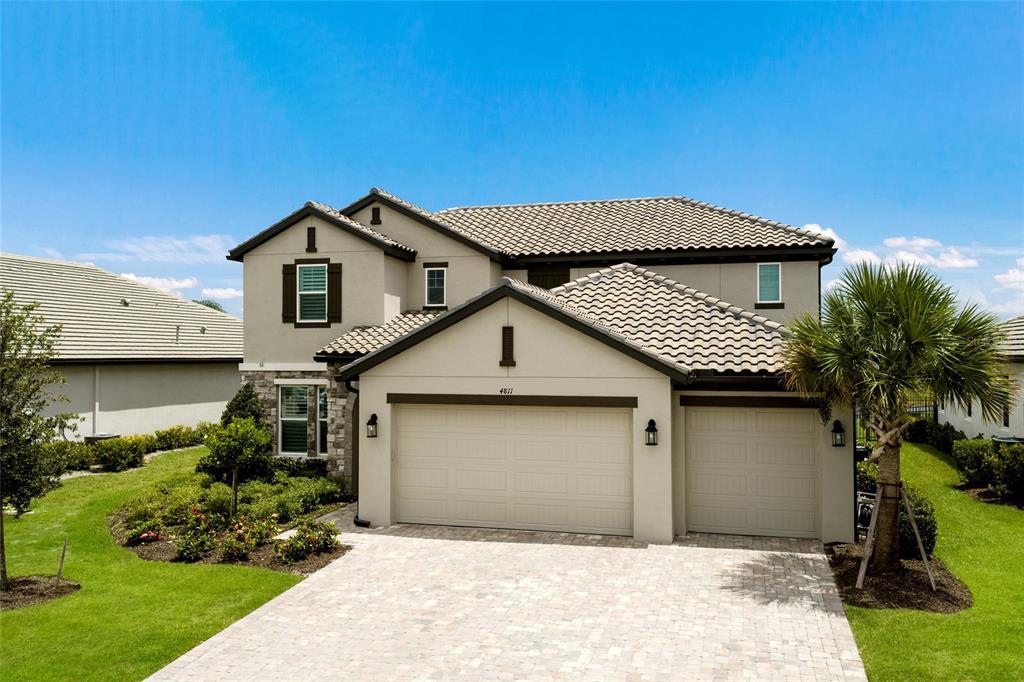 A two-story suburban house features a beige stucco exterior, a tiled roof, and a paved driveway — 4811 HONEY DEW LANE, BRADENTON, FL