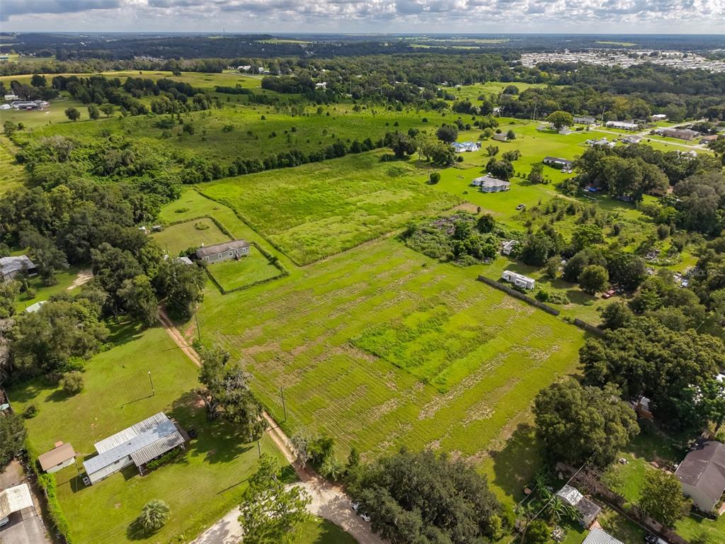 An aerial view shows a large, grassy rural lot with a house and surrounding trees — 7408 HYLAN STREET, ZEPHYRHILLS, FL