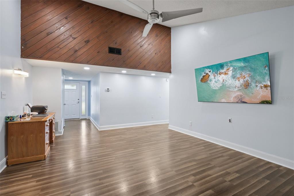 A living room features wood-paneled vaulted ceilings, light blue walls, and wood-look flooring — 3613 COPPERTREE CIRCLE, BRANDON, FL