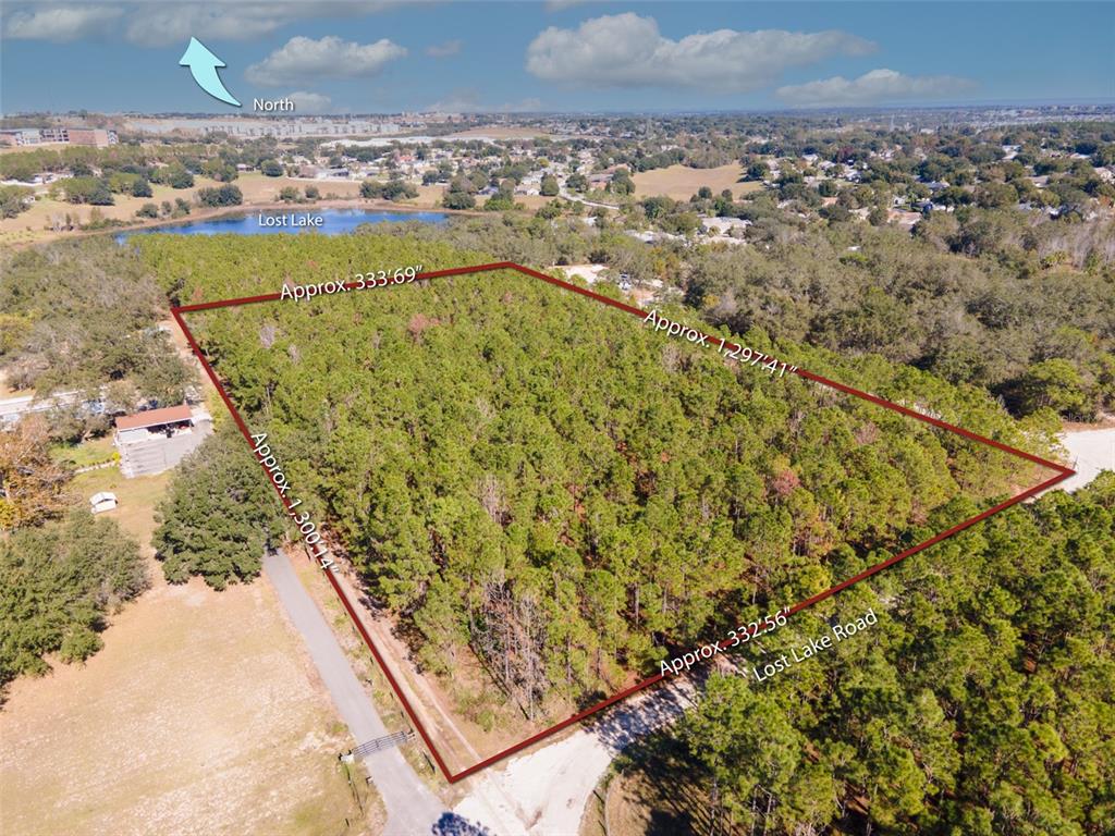 An aerial view shows a rectangular, wooded plot of land outlined in red — LOST LAKE ROAD, CLERMONT, FL