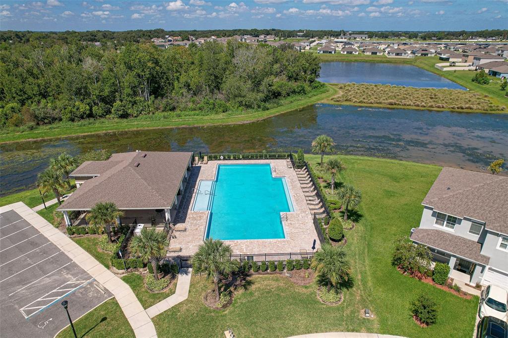 An aerial view shows a community swimming pool and clubhouse adjacent to a pond — 759 AUBURN GROVE COURT, AUBURNDALE, FL