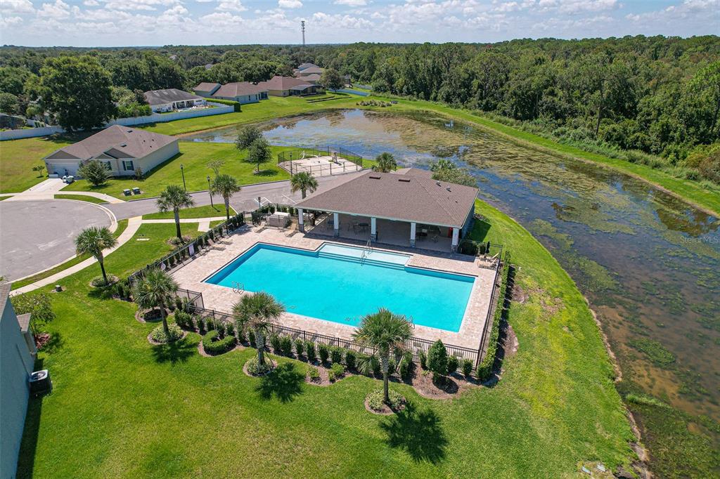 An aerial view shows a community swimming pool and covered pavilion next to a pond — 759 AUBURN GROVE COURT, AUBURNDALE, FL