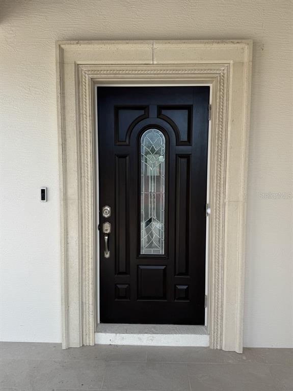A dark brown front door with a glass insert is framed by decorative stone molding — 1911 SW 7TH AVENUE, OKEECHOBEE, FL