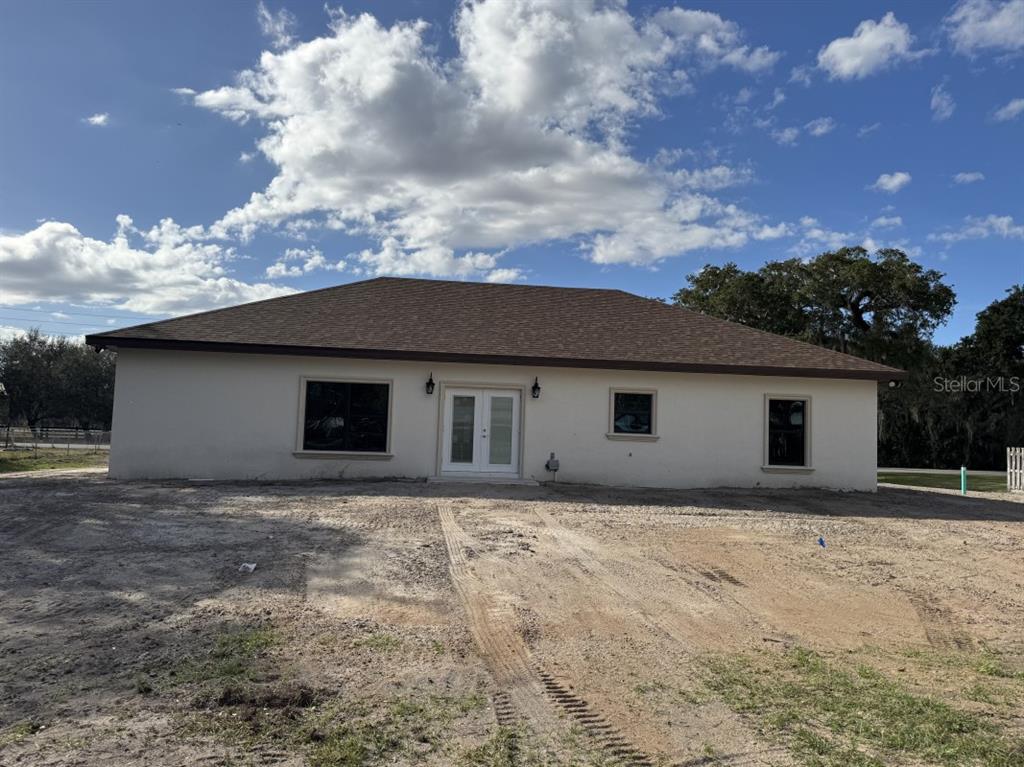 A single-story house with a light-colored stucco exterior and a brown shingled roof — 1911 SW 7TH AVENUE, OKEECHOBEE, FL
