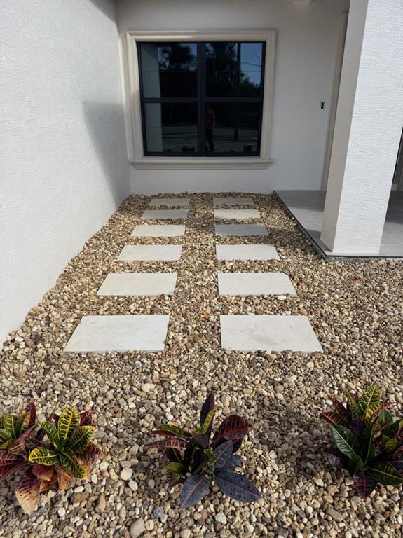 A stone paver walkway leads to a window on the side of a white house — 1911 SW 7TH AVENUE, OKEECHOBEE, FL