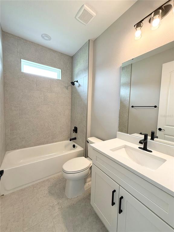 A bathroom features a white vanity, a toilet, and a tiled bathtub-shower combination — 4645 BOSTON STREET, SEBRING, FL