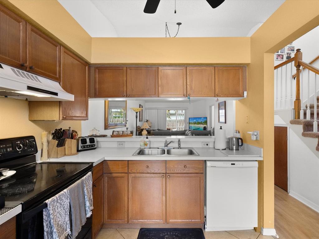 A kitchen features wood cabinets, white countertops, a double sink, and a white dishwasher — 2538 W BROOK LANE, CLEARWATER, FL