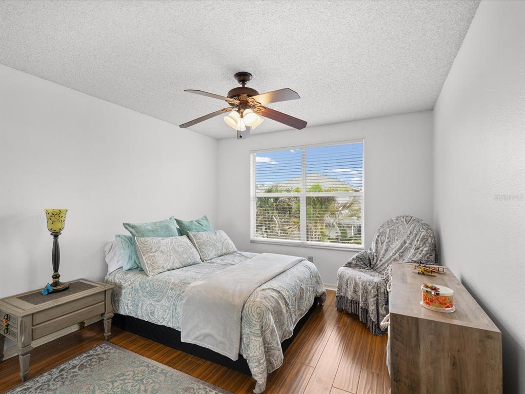 A bedroom features a bed with patterned bedding, a ceiling fan, and a wooden dresser — 2538 W BROOK LANE, CLEARWATER, FL
