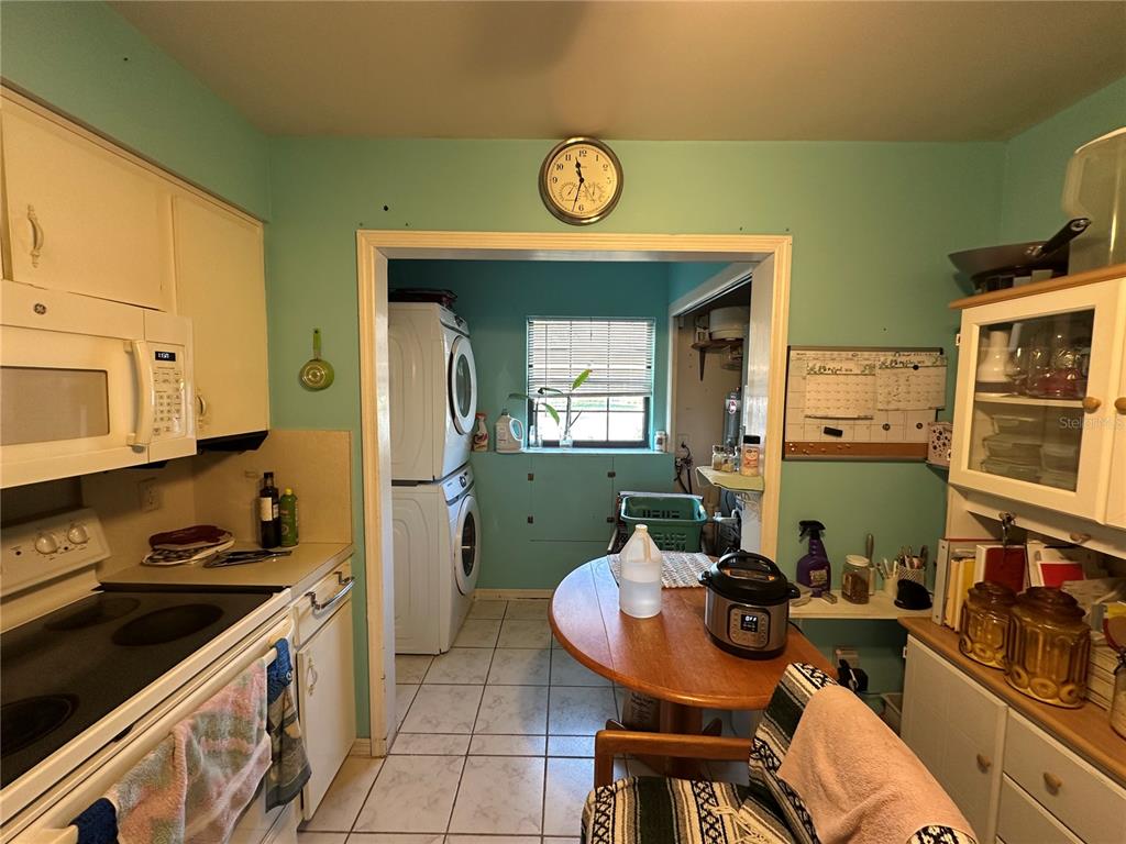 A kitchen with light green walls, white cabinets, a round wooden table, and laundry appliances — 913 MICHIGAN AVENUE, ST CLOUD, FL