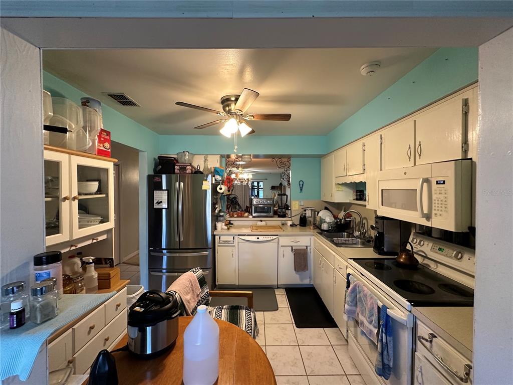 A kitchen with white cabinets, stainless steel appliances, and light blue walls — 913 MICHIGAN AVENUE, ST CLOUD, FL