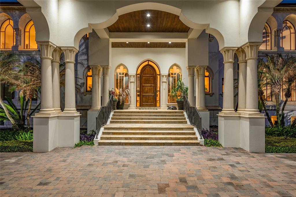 A grand arched entryway with stone steps, columns, and a wooden door at night — 5603 MARLEON DRIVE, WINDERMERE, FL