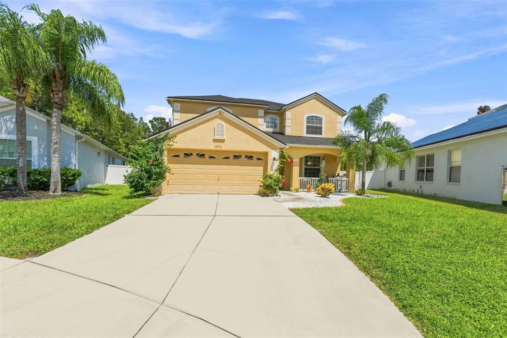 A two-story suburban house with a tan stucco exterior and a two-car garage — 15731 CEDAR ELM TERRACE, LAND O LAKES, FL