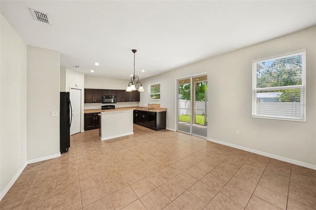 A kitchen with dark cabinets, tile flooring, and a sliding glass door leading to a patio — 1102 CANYON OAKS DRIVE, BRANDON, FL