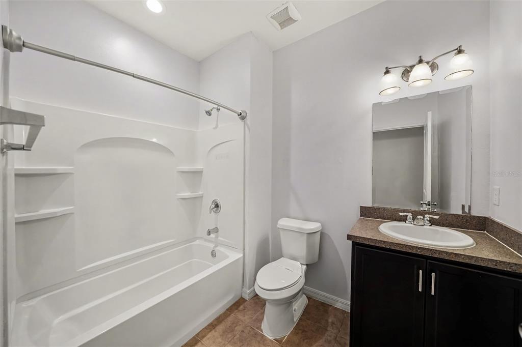 A bathroom features a white tub-shower combo, a toilet, and a vanity with a dark cabinet — 1102 CANYON OAKS DRIVE, BRANDON, FL