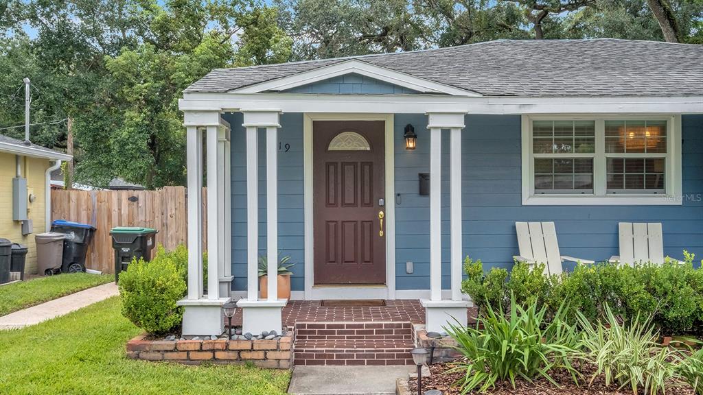 A blue house exterior features a covered front porch with white columns and a brown door — 1819 LAKE SUE DRIVE, ORLANDO, FL