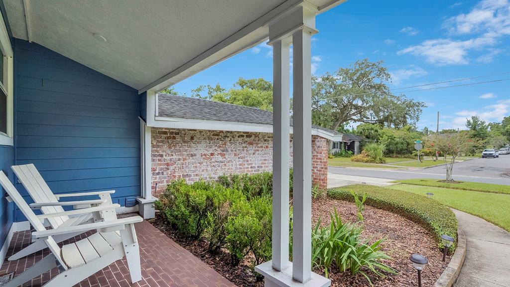 A covered brick porch features white Adirondack chairs, a blue wall, and a brick exterior — 1819 LAKE SUE DRIVE, ORLANDO, FL