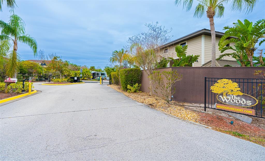 A paved driveway leads to the gated entrance of an RV resort with palm trees — 6861 AMANDA VISTA CIRCLE, LAND O LAKES, FL