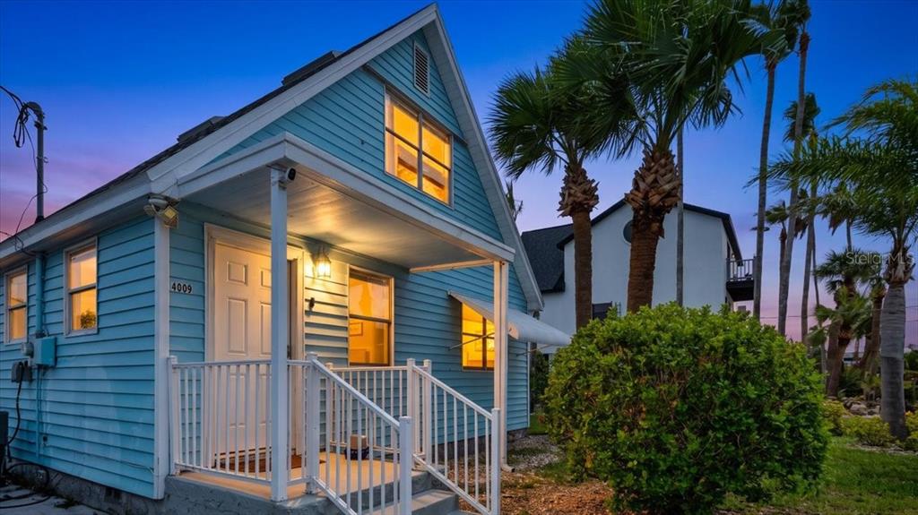 A light blue house with a front porch and white railings stands under a twilight sky — 4009 CASA COURT, HERNANDO BEACH, FL