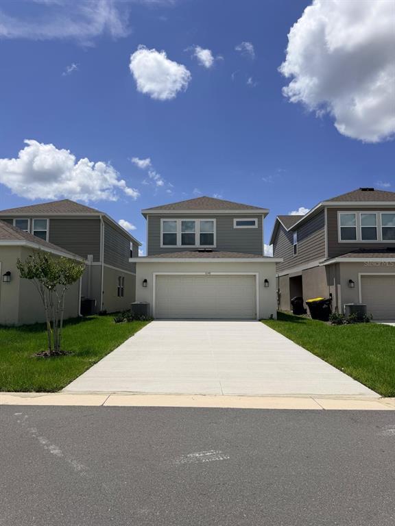 A two-story suburban house with a beige stucco facade and a two-car garage — 6048 ZEN WAY, CLERMONT, FL