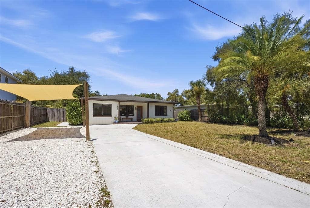 A single-story house with a concrete driveway, a shade sail, and palm trees — 4925 REMINGTON DRIVE, SARASOTA, FL