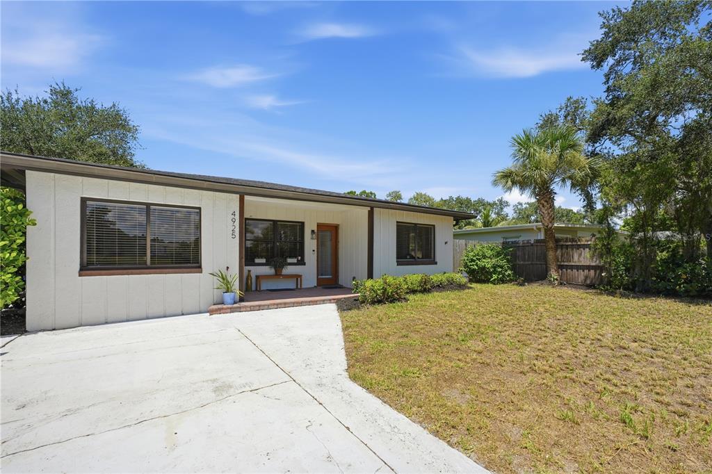 A single-story house with white siding, a concrete driveway, and a small front lawn — 4925 REMINGTON DRIVE, SARASOTA, FL