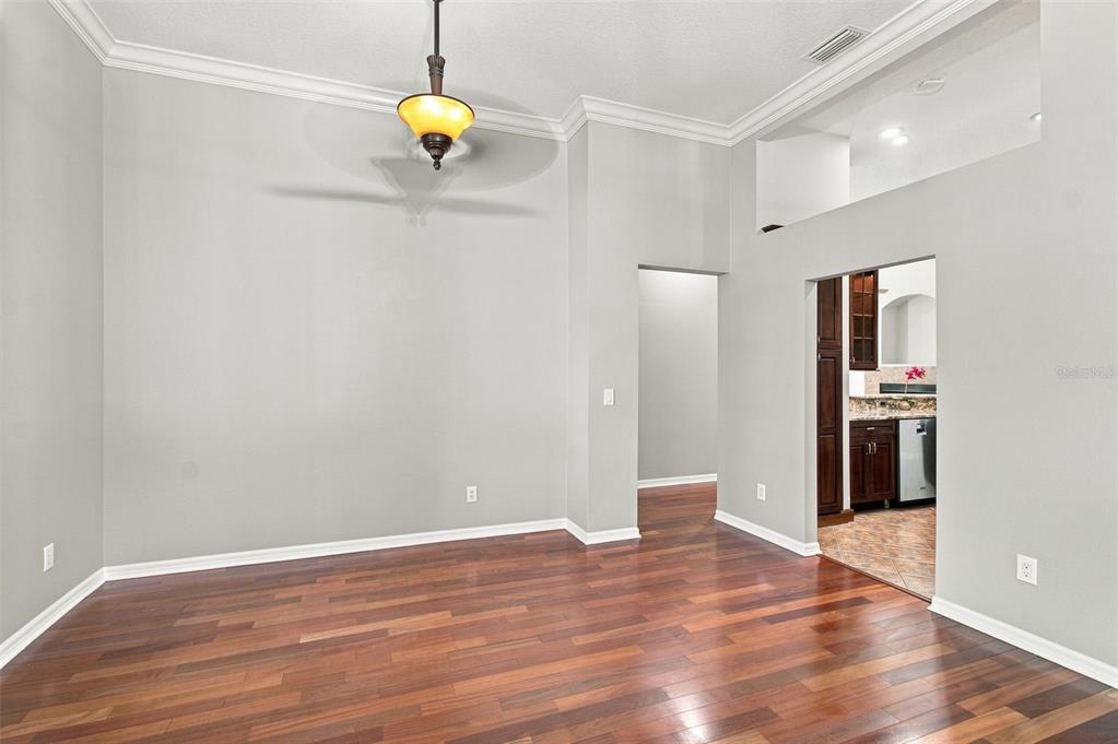 An empty room with hardwood floors, a ceiling fan, and an arched doorway to a kitchen — 10113 CANNON DRIVE, RIVERVIEW, FL